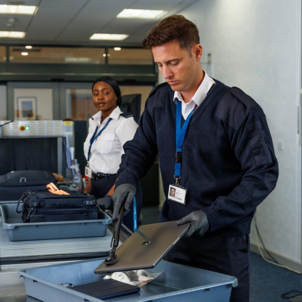 Male and female security staff checking baggage