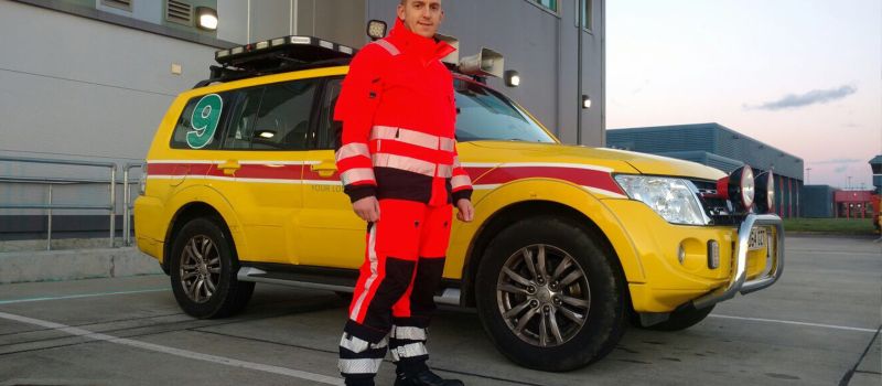Gatwick Airport airside employee in orange and black hi vis suit