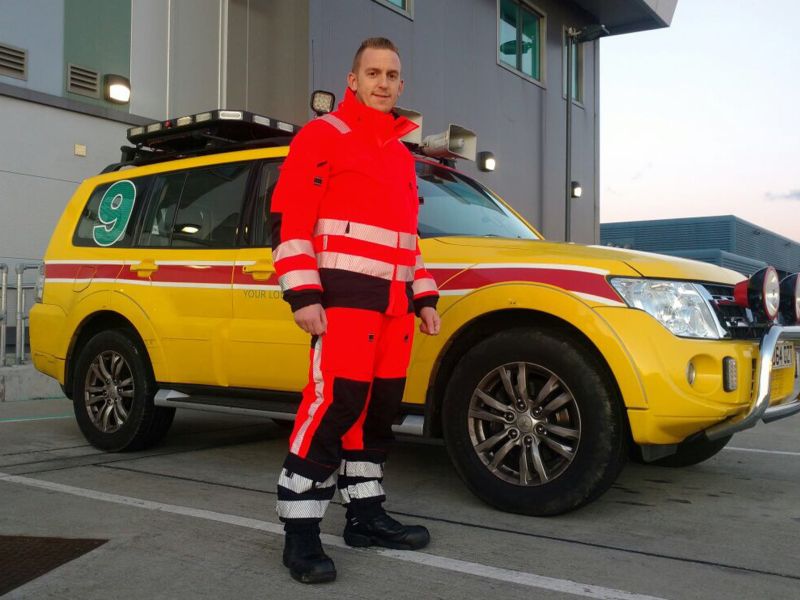 Gatwick Airport airside employee in orange and black hi vis suit