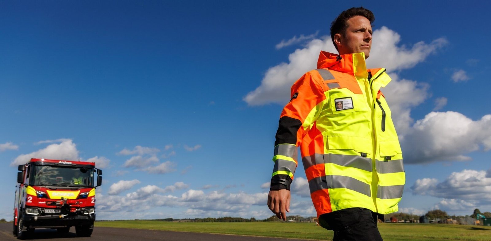 Airfield Ops inspecting runway with fire engine in the background. Showcasing aviation  PPE