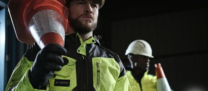 Night traffic workers carrying traffic cone.