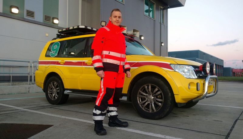 Gatwick Airport airside employee in orange and black hi vis suit